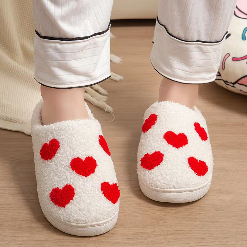 Fitlybuy white, fuzzy Nordic slippers with red heart patterns, worn on a wood floor with white pajamas.