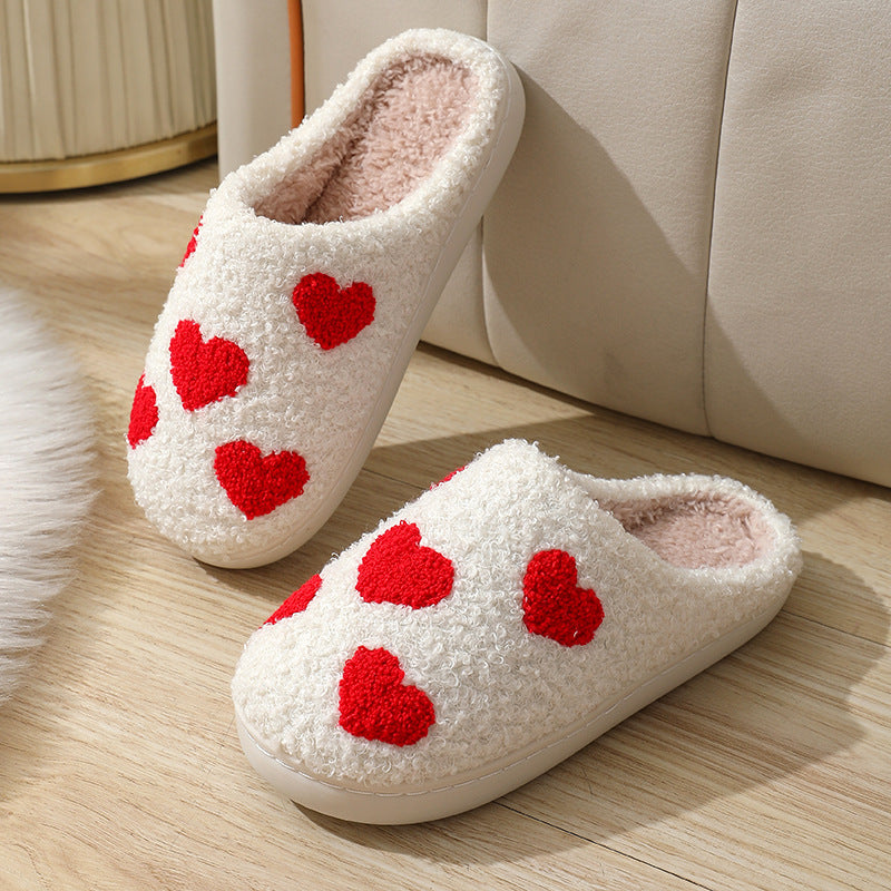 Fitlybuy Nordic memory foam slippers in white fleece with red heart patterns, shown on a wooden floor.