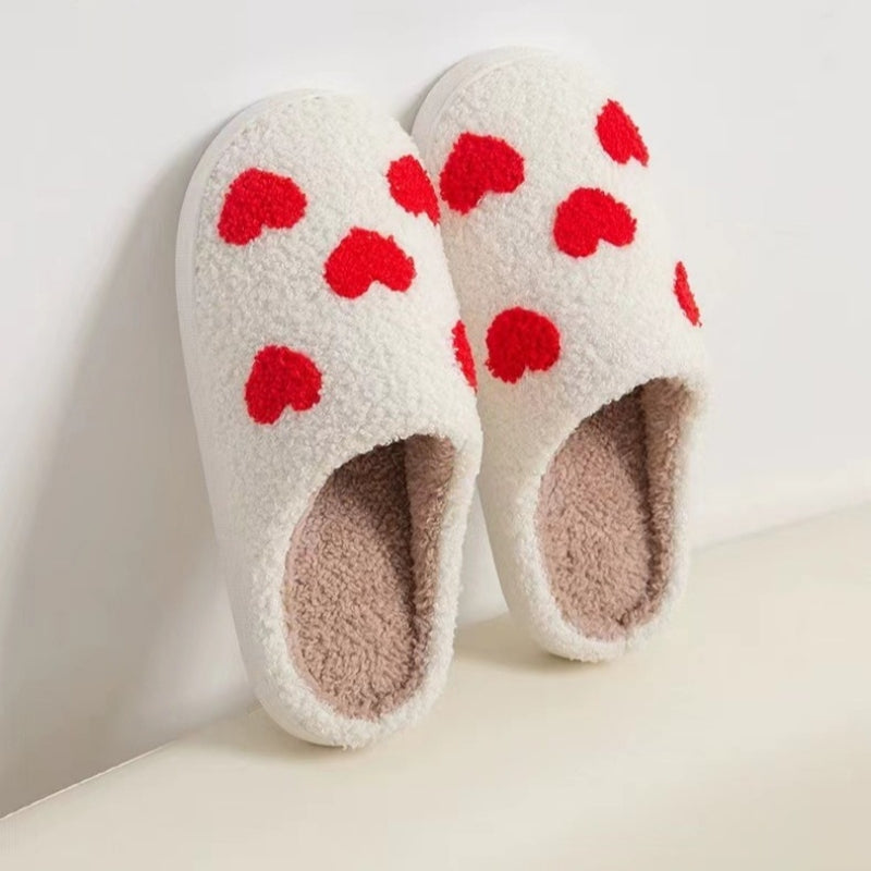Fitlybuy Nordic memory foam slippers in white fleece with red hearts, leaning against a white wall.