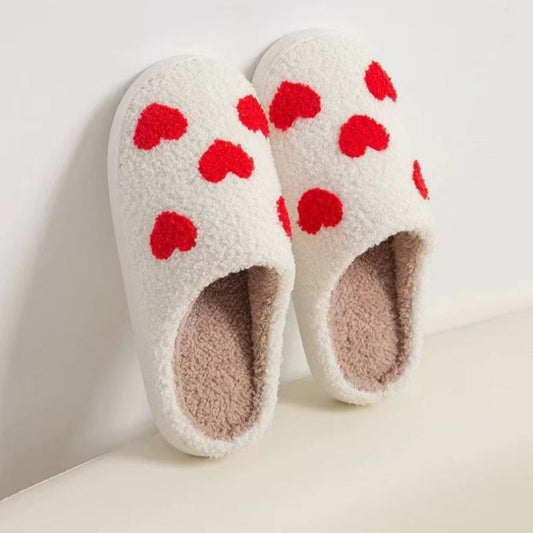 Fitlybuy Nordic memory foam slippers in white fleece with red hearts, leaning against a white wall.