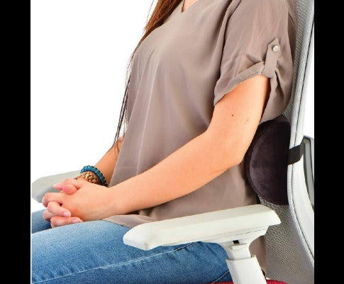 Black ergonomic memory foam lumbar support cushion attached to a mesh office chair behind a seated woman.
