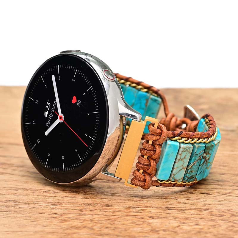 Fitlybuy smartwatch with a turquoise stone and brown woven cord bracelet, resting on a wooden surface.