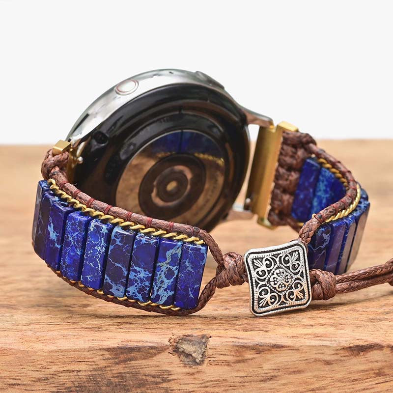 Fitlybuy blue stone cylindrical bracelet watch band with brown woven cord and silver ethnic charm on wood surface.