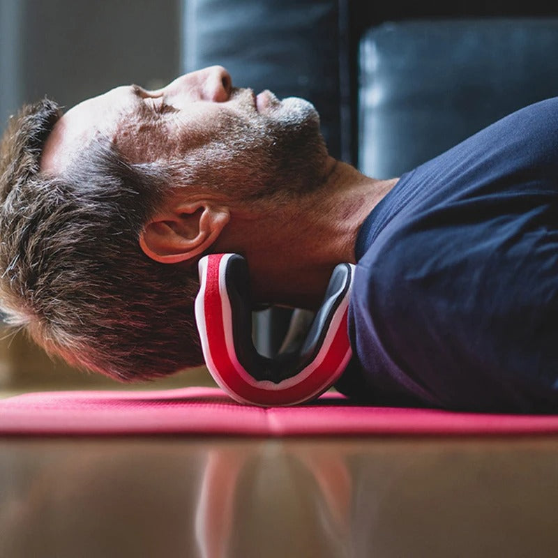 Man lying on a red mat using a black and red Fitlybuy ergonomic orthopedic neck traction stretcher for pain relief.