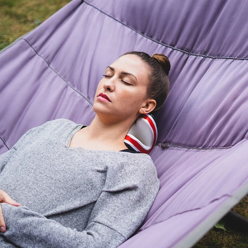 Woman lying in a purple hammock using a Fitlybuy white, red, and black ergonomic orthopedic neck stretcher.