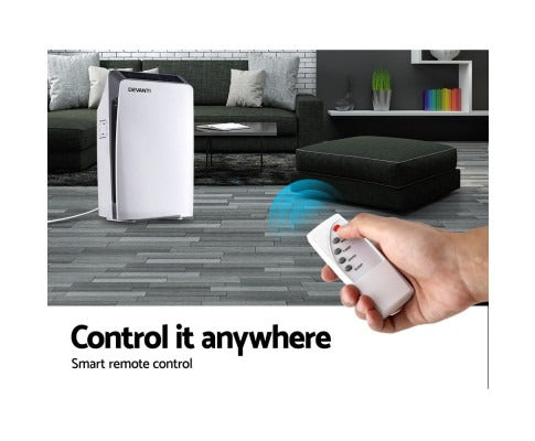 White Fitlybuy X100 HEPA air purifier in a modern living room, controlled by a handheld remote.