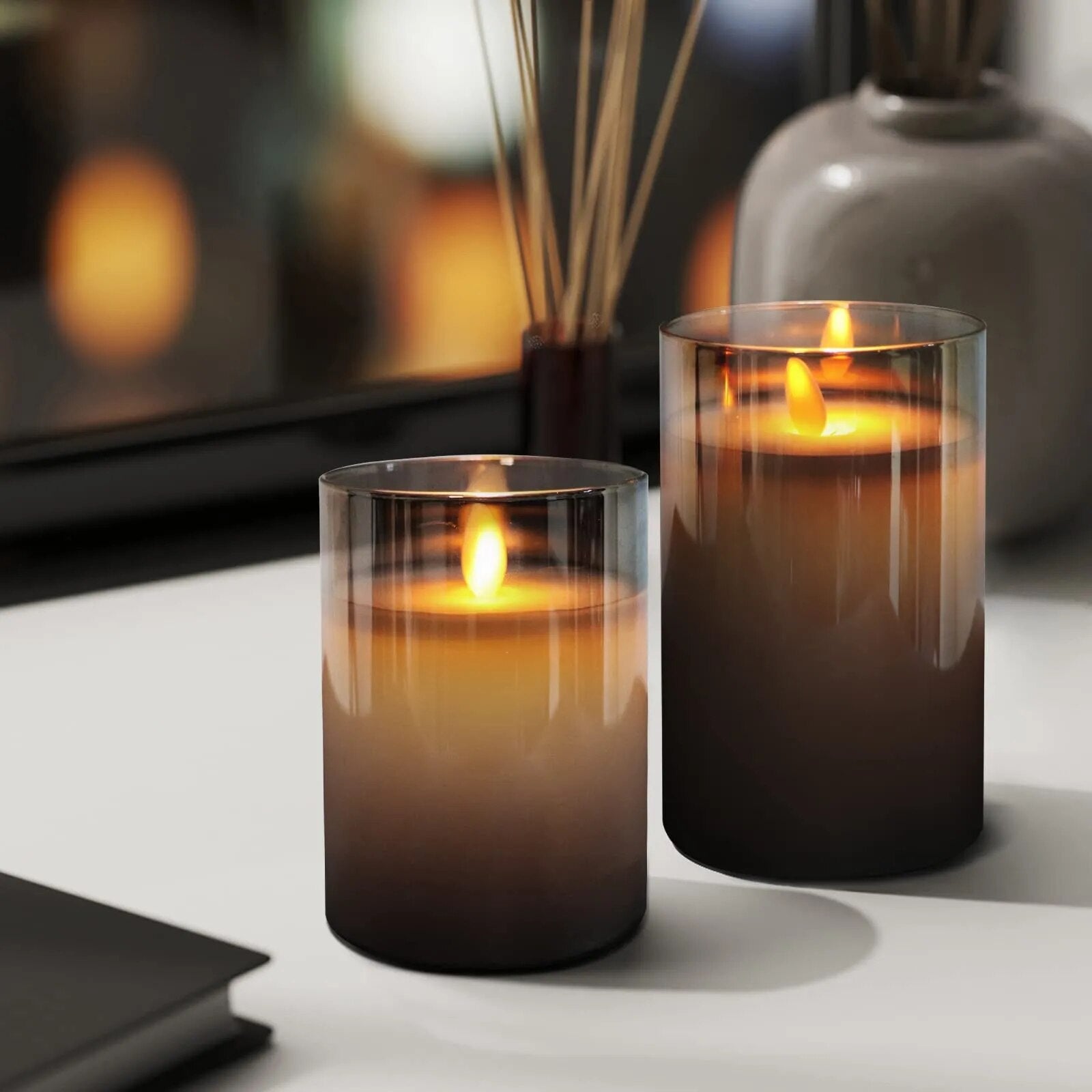 Fitlybuy AuraFlame LED flameless candles in gradient grey glass cylinders glowing with realistic warm flickering flames.