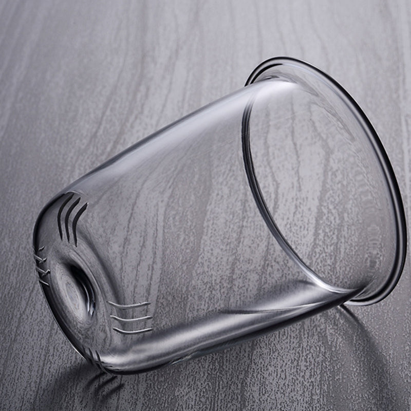Clear glass tea infuser basket for the Pindefang teapot, resting on a gray wood-grain surface.