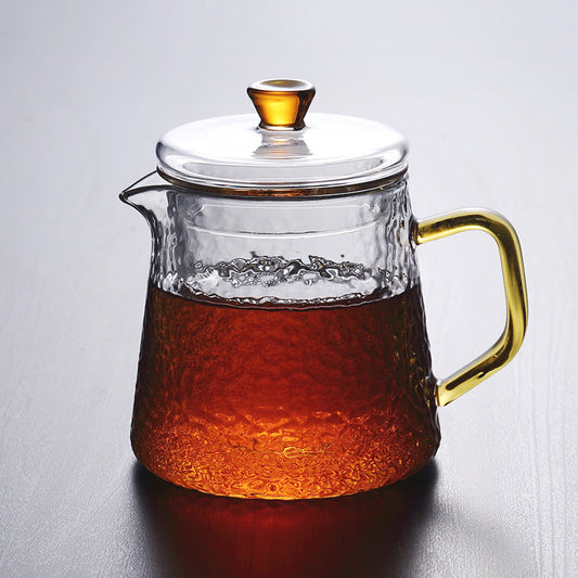 Fitlybuy glass teapot with amber handle and lid, featuring a textured design filled with dark tea on a gray surface.
