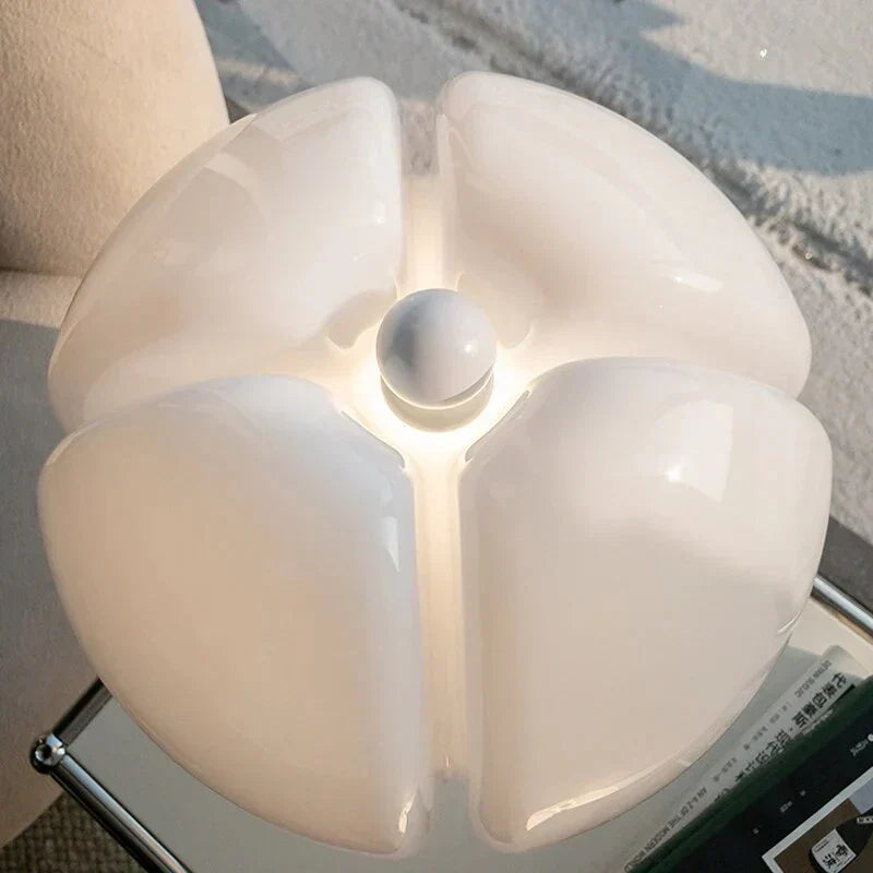 Top view of white, petal-shaped Fitlybuy FloraLuxe LED table lamp on a modern side table with a book.