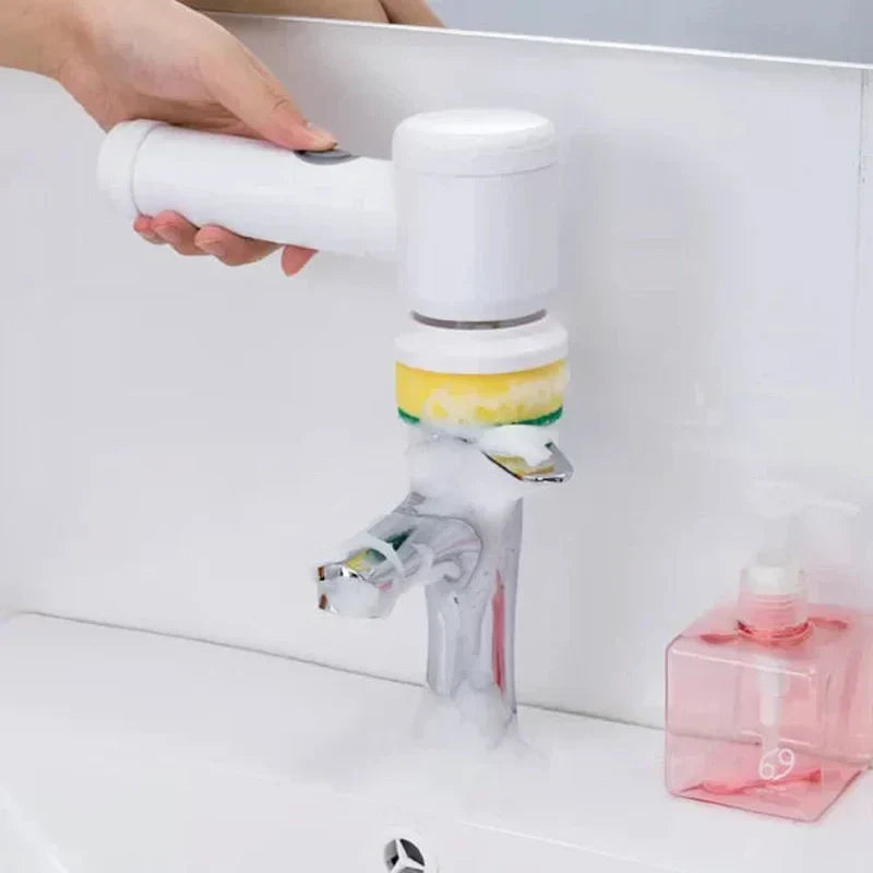 Hand using a white Fitlybuy cordless electric scrubber with a sponge head to clean a soapy bathroom faucet.