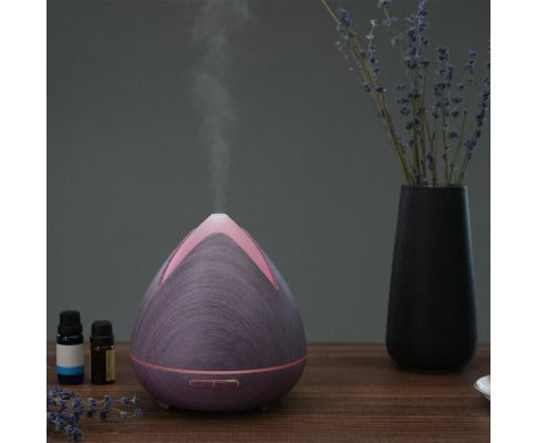 Fitlybuy PureSpa purple wood-grain ultrasonic diffuser releasing cool mist on a table with lavender and oil bottles.