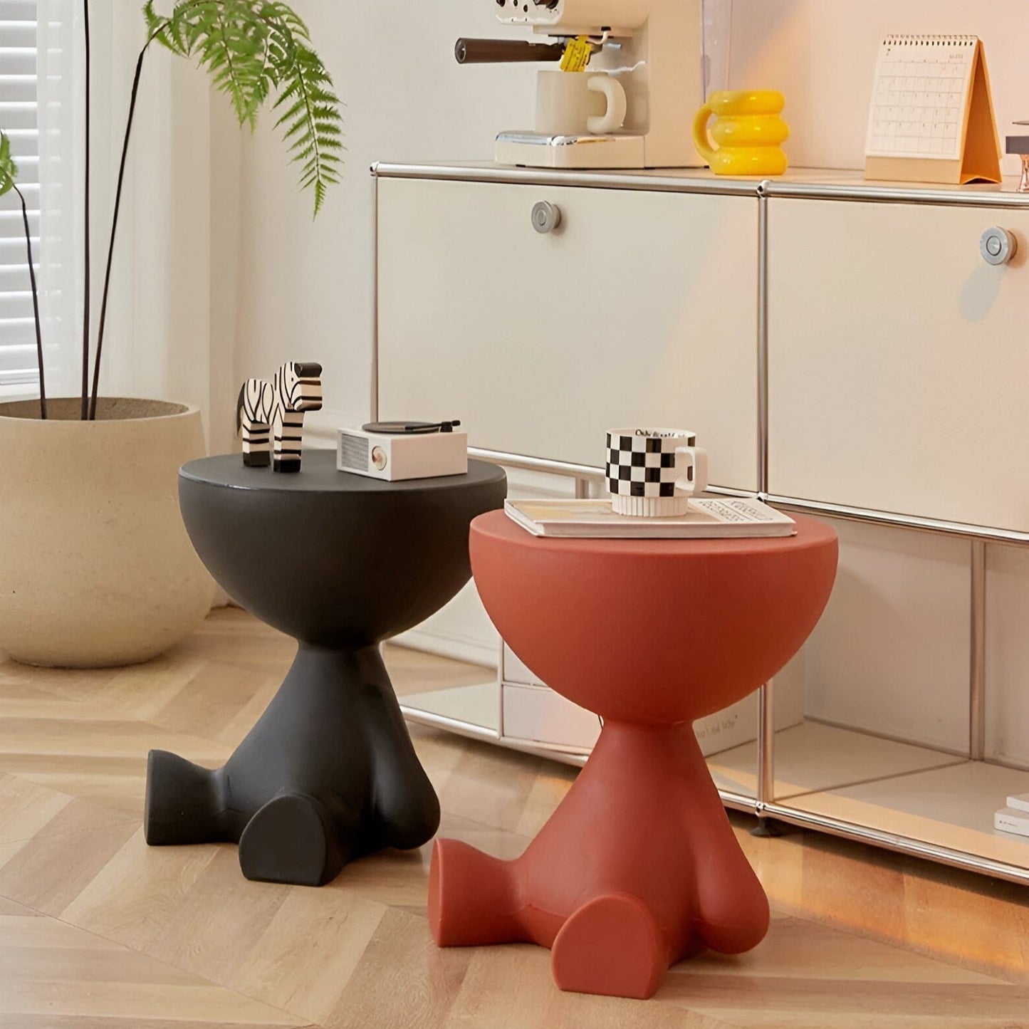 Fitlybuy Ylix round coffee tables with artisan bear-shaped bases in matte black and terracotta red in a modern room.