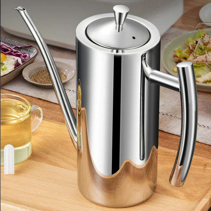Fitlybuy stainless steel oil dispenser with long spout and handle on a wooden kitchen counter, near plates of food.