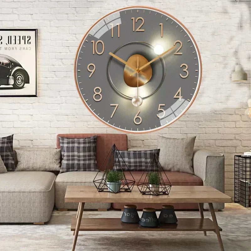 Fitlybuy silent classic wall clock: gray round face with gold numbers and hands, hanging on a brick wall in a living room.