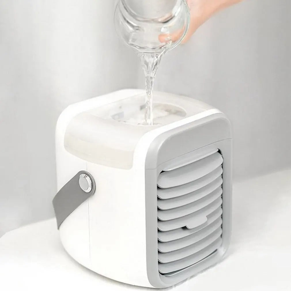 White and grey Fitlybuy 3-in-1 portable mini air conditioner being filled with water from a glass.