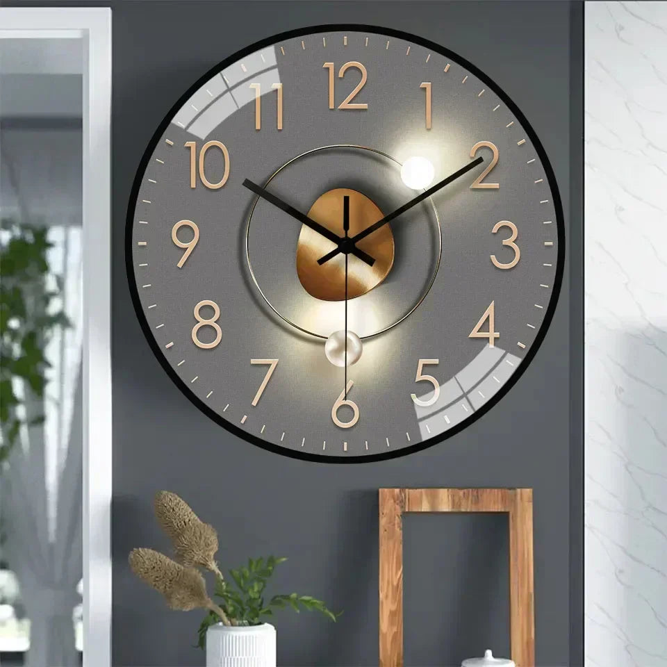 Fitlybuy silent wall clock with a grey dial, gold numerals, and elegant central design, mounted on a dark grey wall.