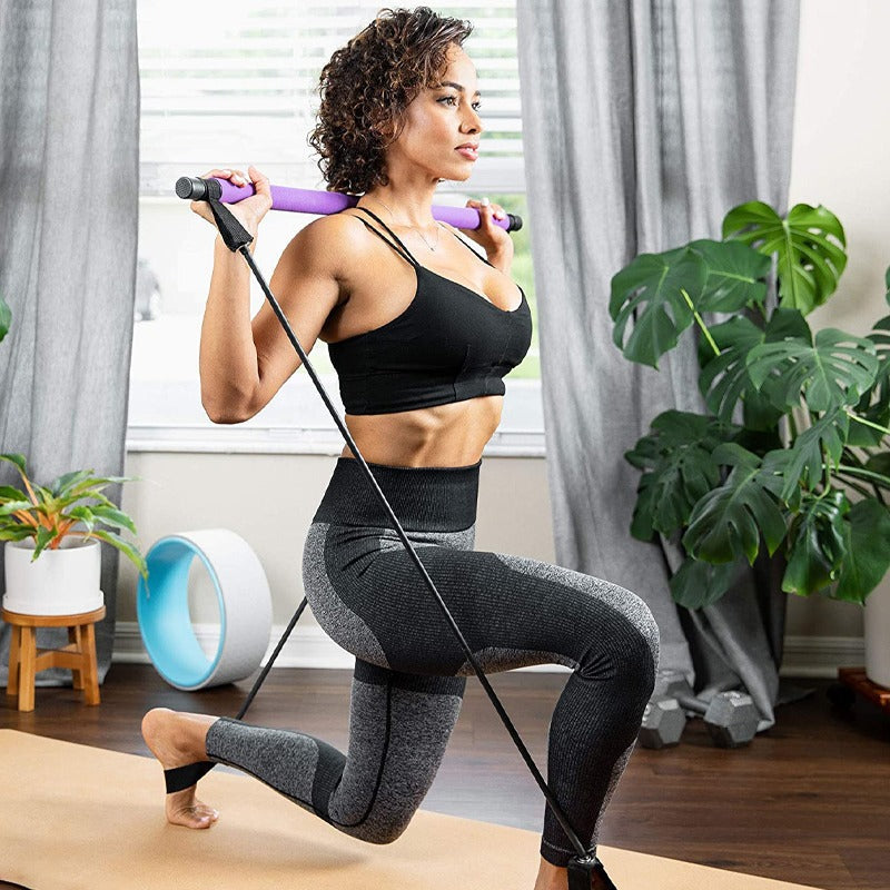 Woman doing a lunge with a purple Fitlybuy Pilates bar and resistance bands in a bright, modern home gym.