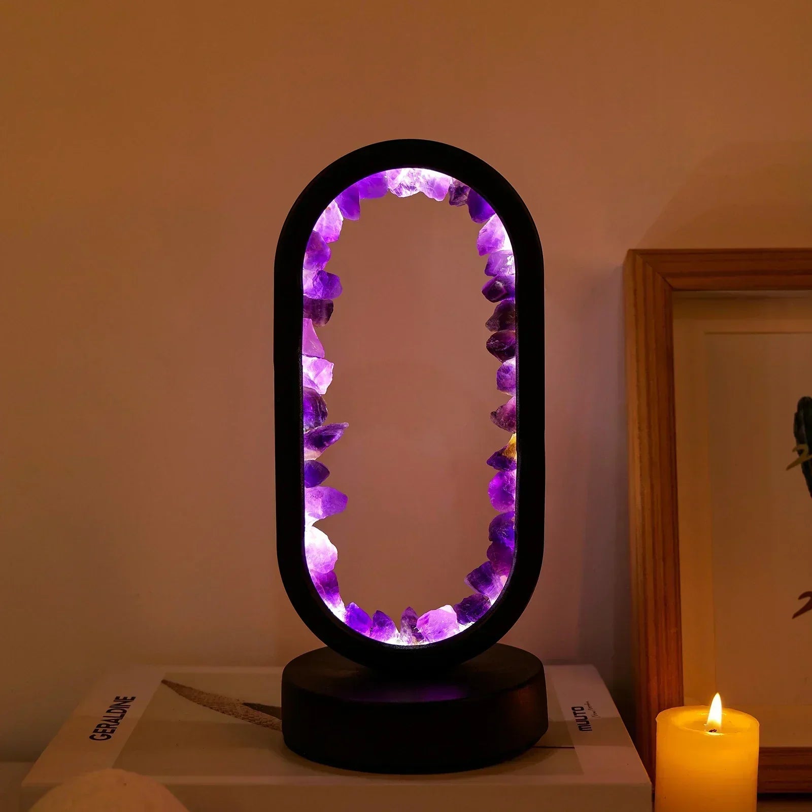 Fitlybuy AuraStone oval lamp with natural purple amethyst crystals glowing with warm light on a table next to a candle.