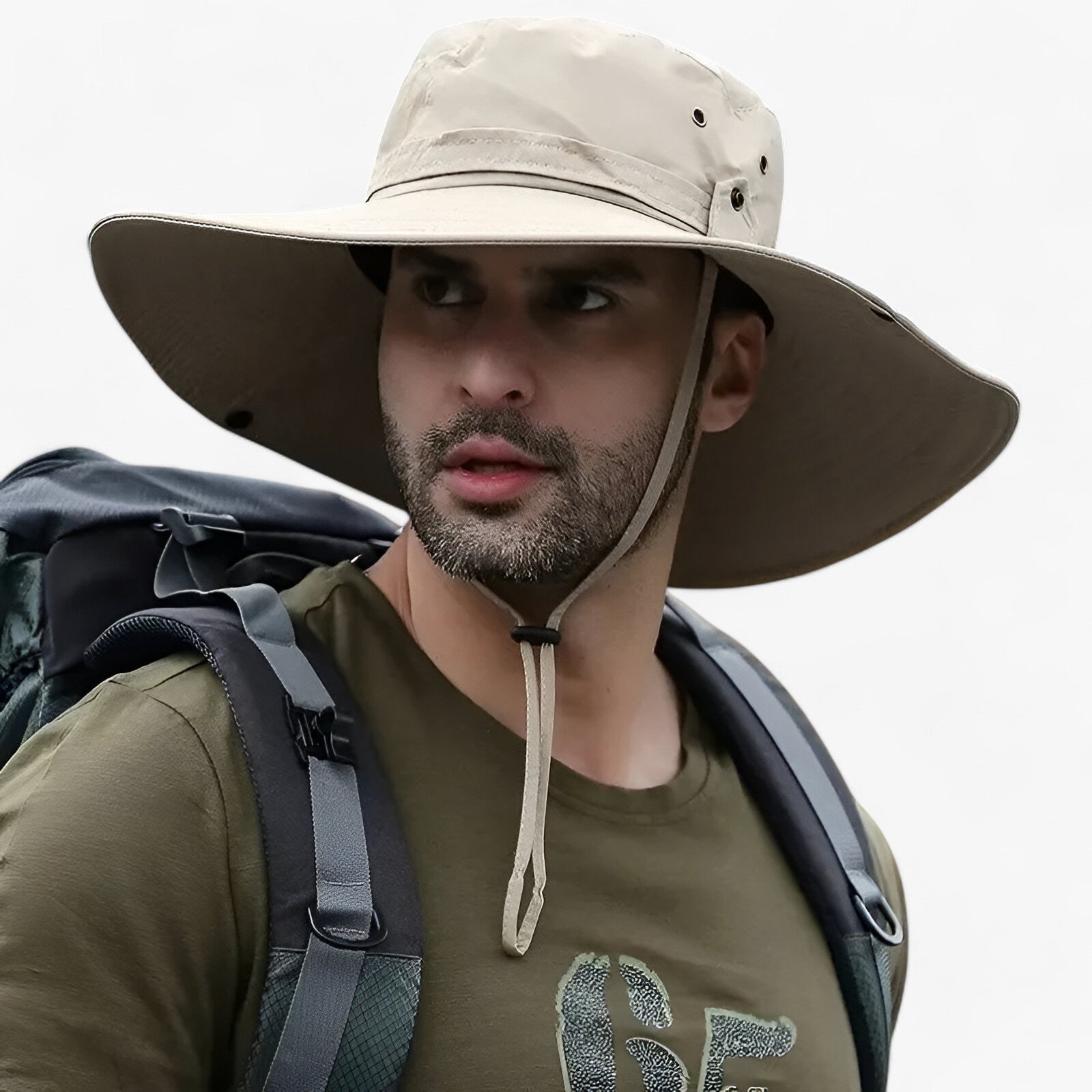Man wearing a beige Fitlybuy Zeno wide-brim UV protection hat with chin strap while hiking with a backpack.