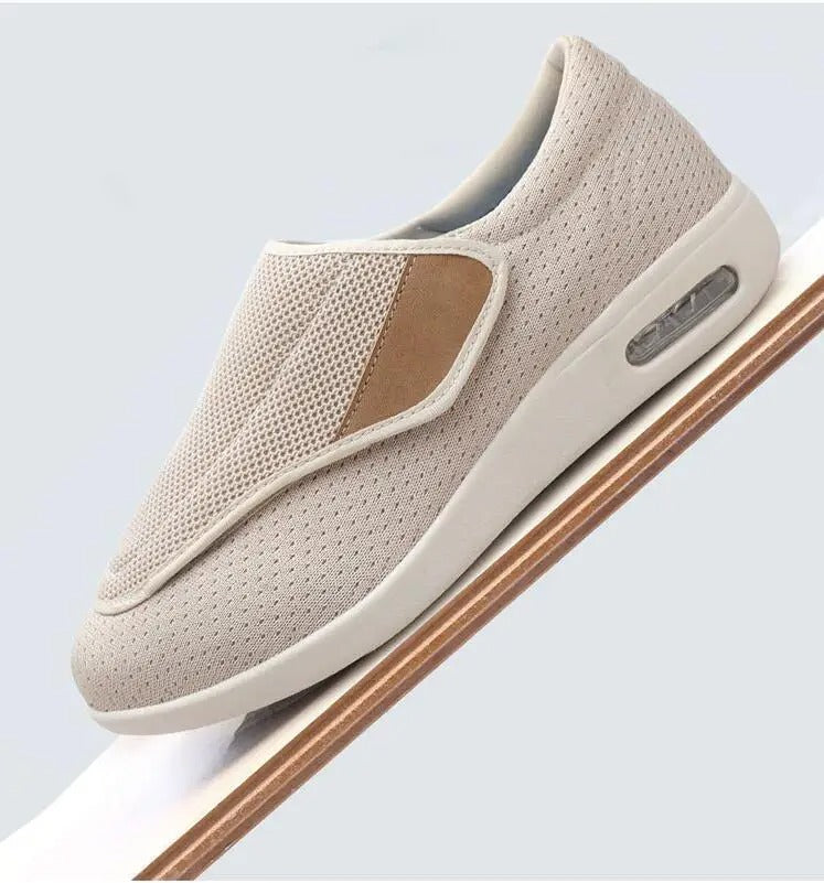 Beige Fitlybuy ComfortStride orthopedic walking shoe with mesh upper, Velcro strap, and air-cushioned sole on an incline.
