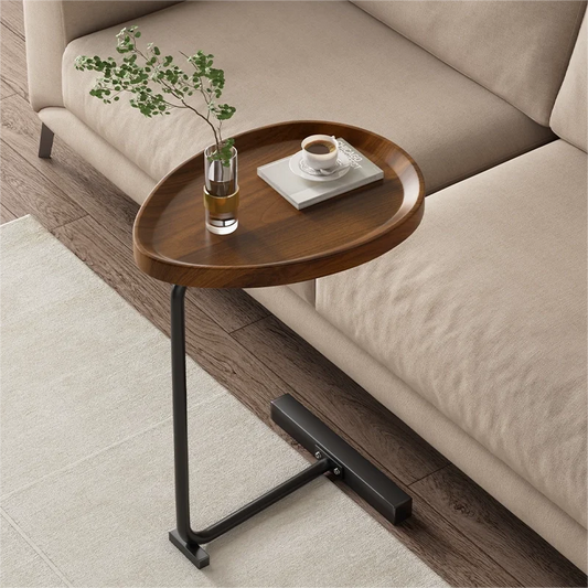 Fitlybuy modern C-shaped side table with a dark wood oval top and black metal base next to a beige living room sofa.