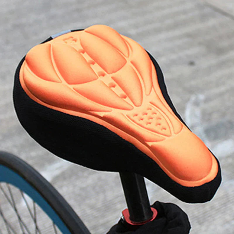 Fitlybuy ComfortRide bike seat cover with orange gel-cushioned top and black fabric sides on a bicycle saddle.