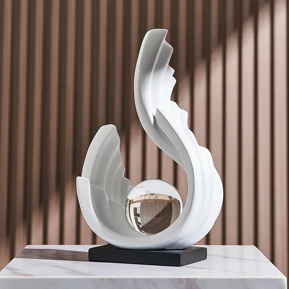Elegant white curved sculpture with a central glass sphere on a black base, set against a modern ribbed wall background.