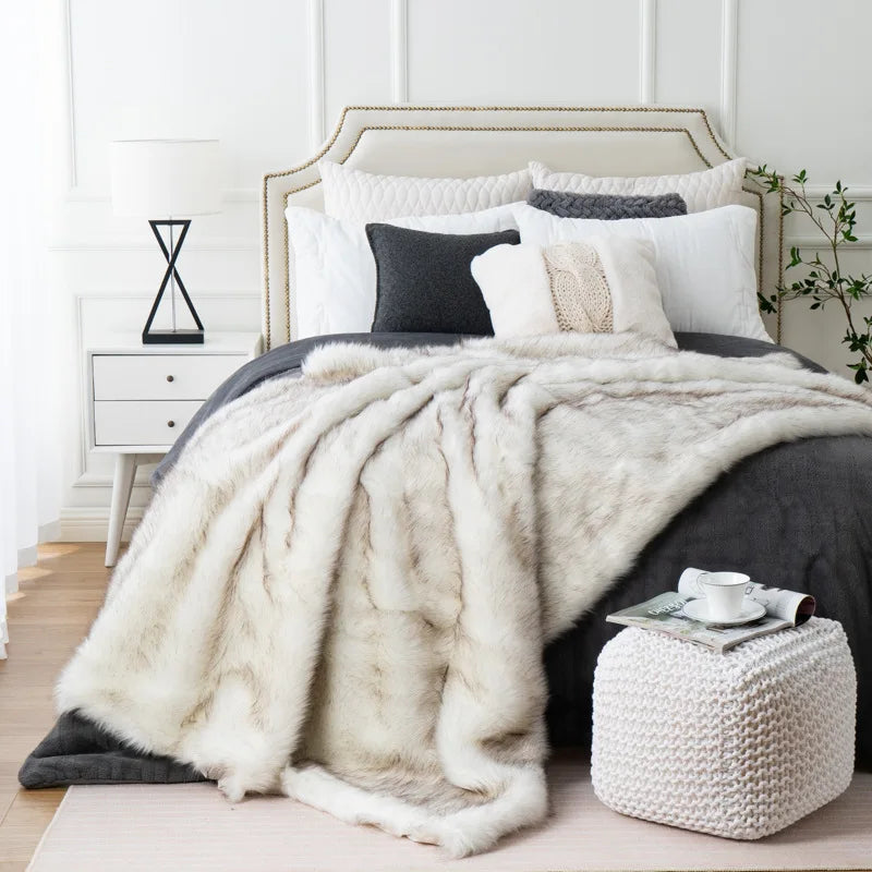 Fitlybuy luxury white faux fox fur throw blanket draped on a dark grey bed in a modern, stylishly decorated bedroom.