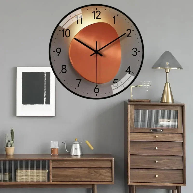 Fitlybuy silent wall clock with a modern orange and grey circular design, hanging above wooden furniture in a room.
