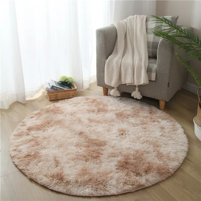 Fitlybuy FluffyMat round rug in beige/brown plush, shown in a cozy living room setting with a chair and houseplant.