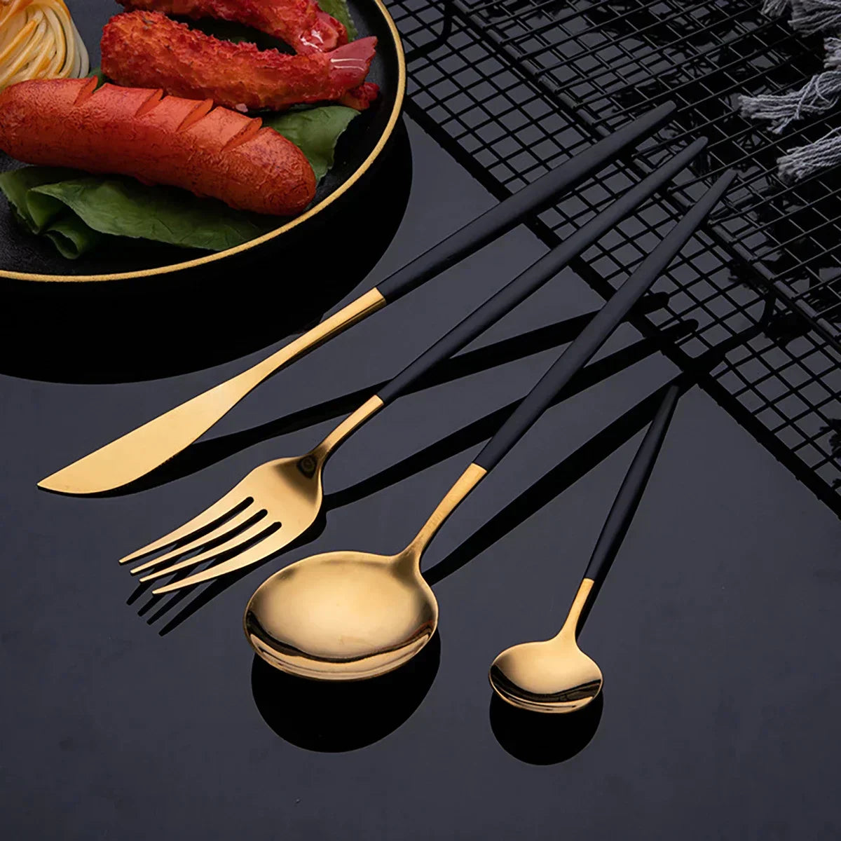 Fitlybuy luxury cutlery set with matte black handles and gold heads, displayed next to a plate of food.