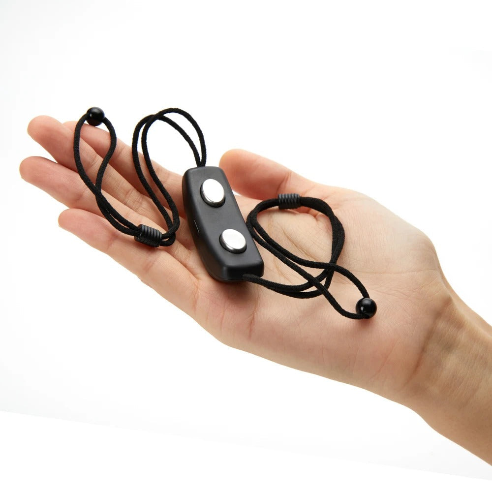 Hand holding a black Fitlybuy smart anti-snoring device with two silver buttons and adjustable black elastic straps.