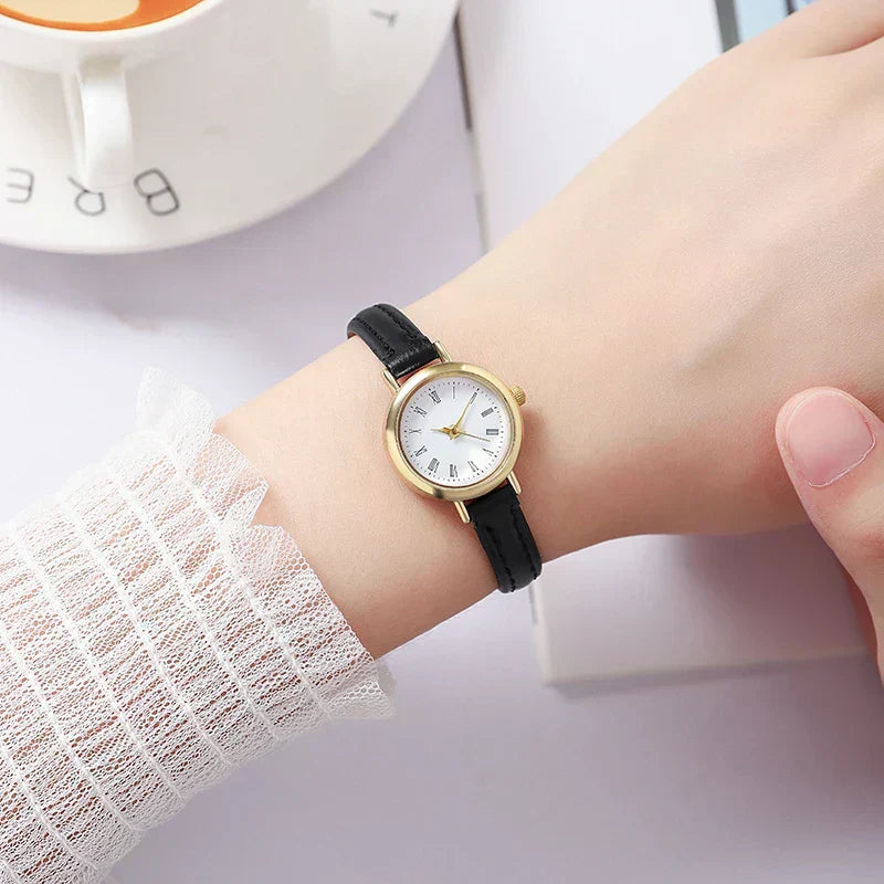Fitlybuy Billie gold women’s watch with a minimalist white face, Roman numerals, and a thin black leather strap.