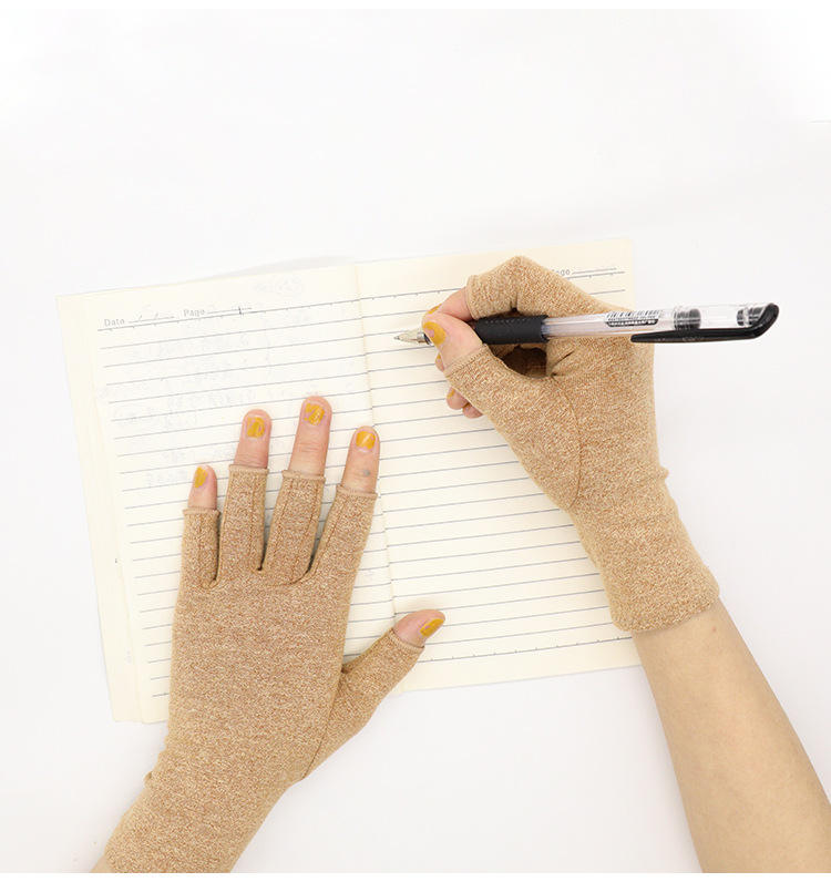 Fitlybuy beige fingerless compression gloves being worn to write in a notebook, showing therapeutic heat technology.