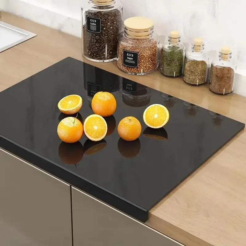 Fitlybuy black acrylic countertop cutting board with lip on a modern kitchen counter with oranges and spice jars.