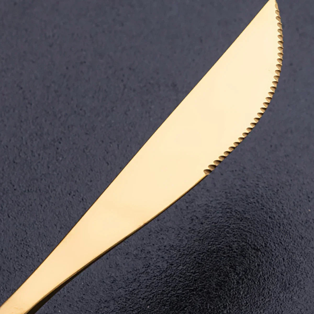 Fitlybuy RoyalMirror luxury gold serrated dinner knife, elegant polished finish, against a dark textured background.