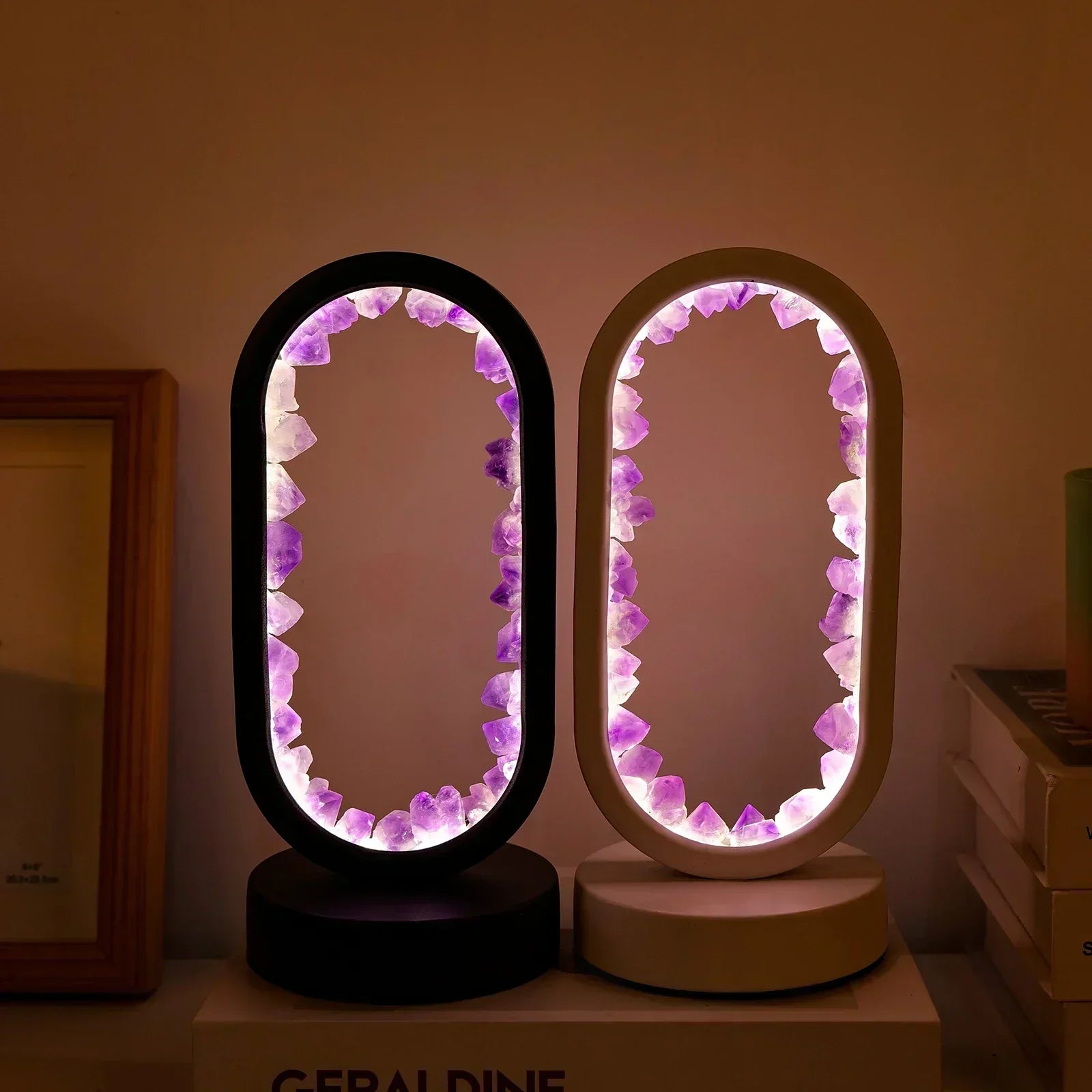 Two oval AuraStone Amethyst lamps with black and white frames, glowing with tranquil purple light on a desk.