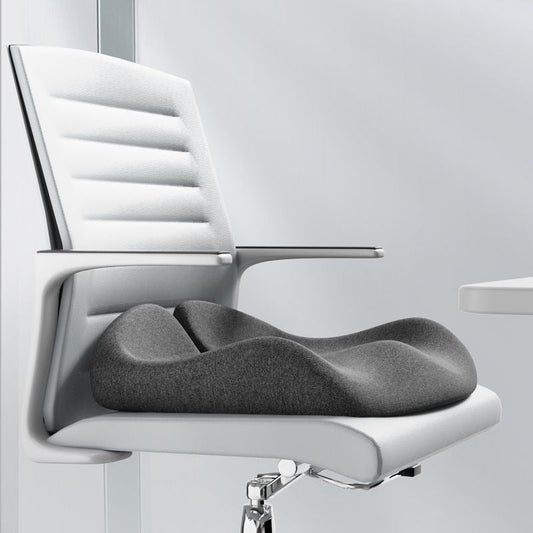 Grey, ergonomic sciatica relief seat cushion on a modern white office chair for back support and comfort.
