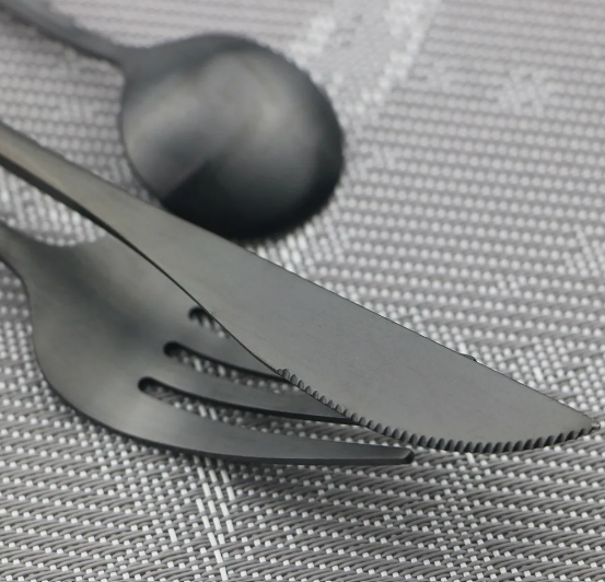 Fitlybuy Torin matte black stainless steel cutlery set with a knife, fork, and spoon on a grey woven placemat.