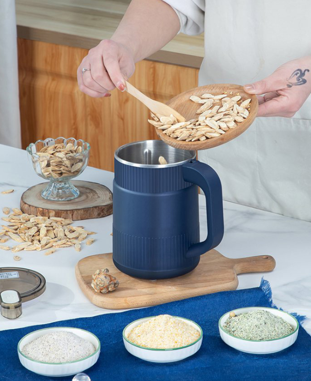 Fitlybuy electric grain mill in navy blue, shown on a wooden board while being filled with seeds in a kitchen setting.
