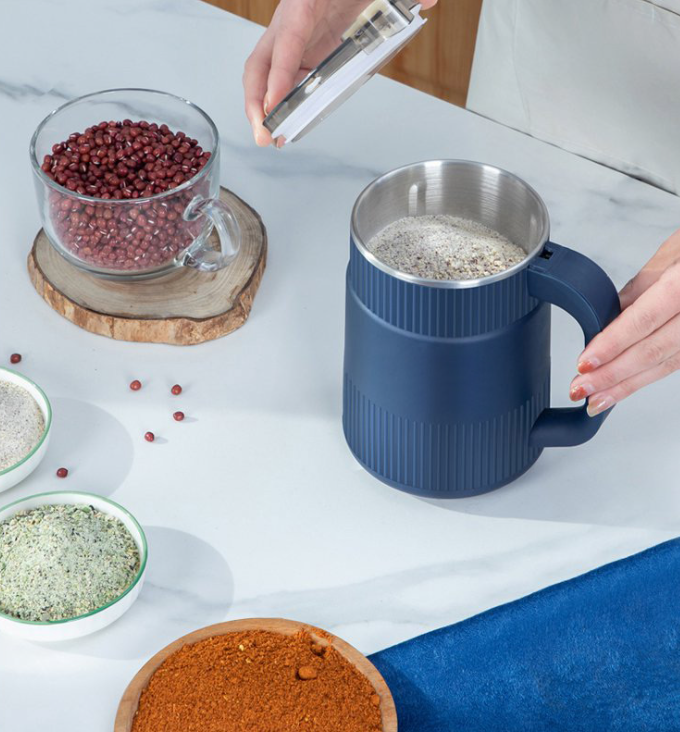 Fitlybuy electric grain mill in navy blue with stainless steel interior, being used to grind beans on a kitchen counter.