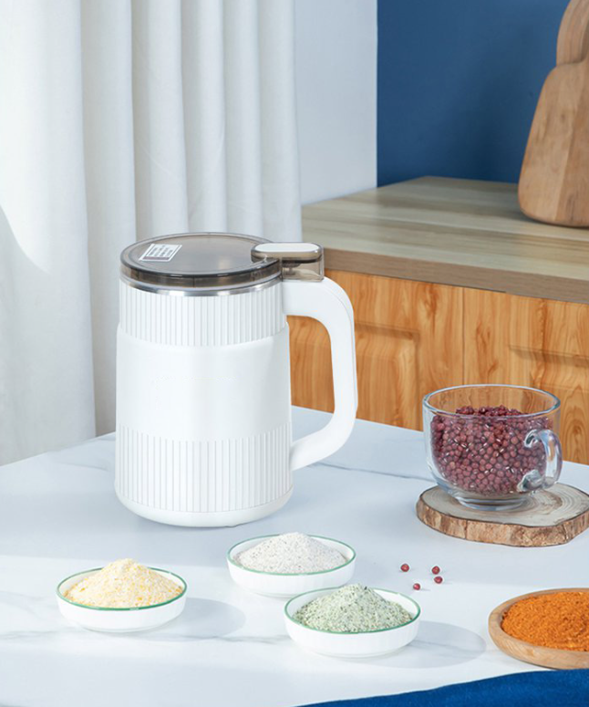 Fitlybuy white electric grain mill with clear lid on a kitchen counter with bowls of ground powder and red beans.