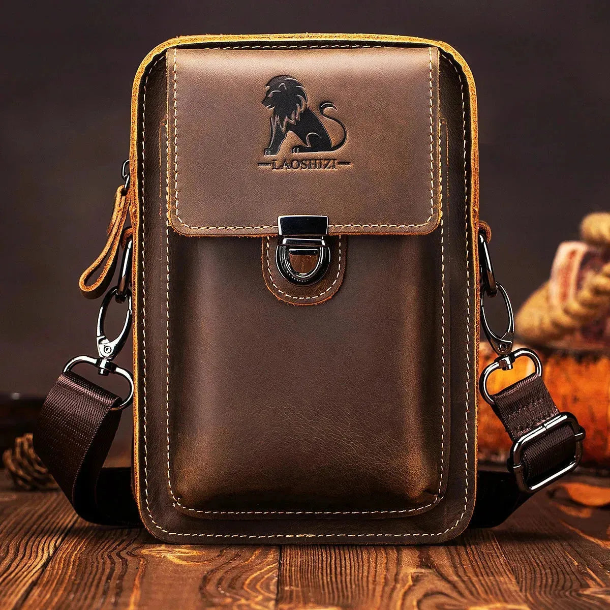 Fitlybuy brown leather waist bag with a lion logo, metal clasp, multi-pocket design, and adjustable strap on wood table.