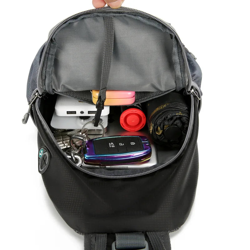 Interior of a black Fitlybuy anti-theft shoulder backpack packed with keys, power bank, umbrella, and accessories.
