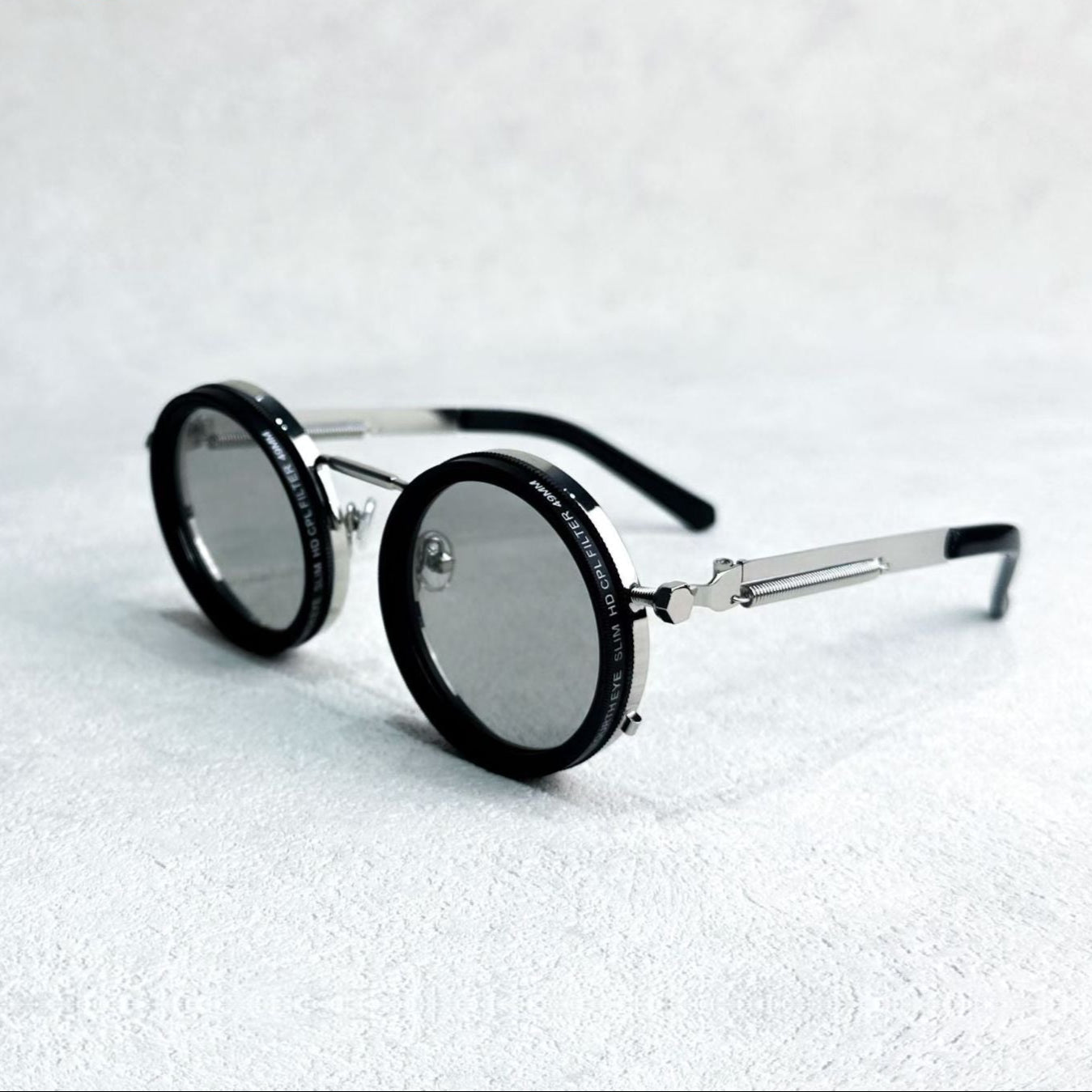 Fitlybuy round polarized unisex sunglasses with silver metal frame, black rims, and adjustable light filters on a white.