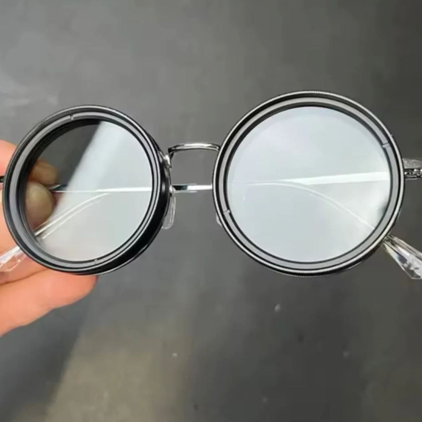 Fitlybuy unisex round polarized sunglasses with silver metal frame and adjustable light-reduction lenses held by hand.