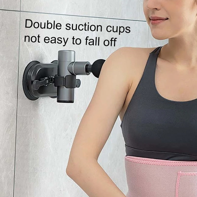 Fitlybuy black wall suction bracket holding a grey massage gun against a tiled wall to massage a person's shoulder.
