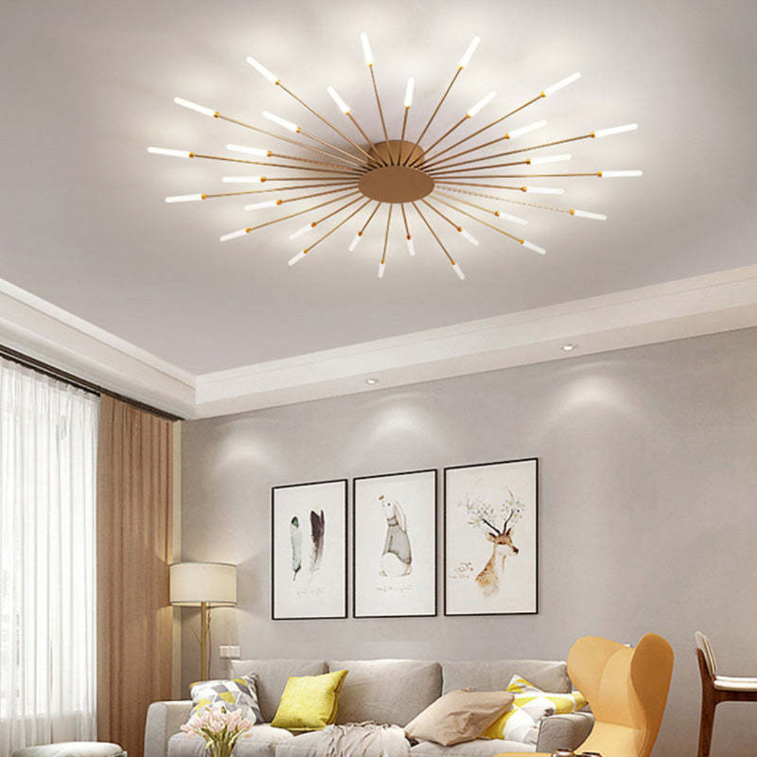 Large starburst LED ceiling light in gold with glowing rod tips, mounted in a modern living room with gray decor.