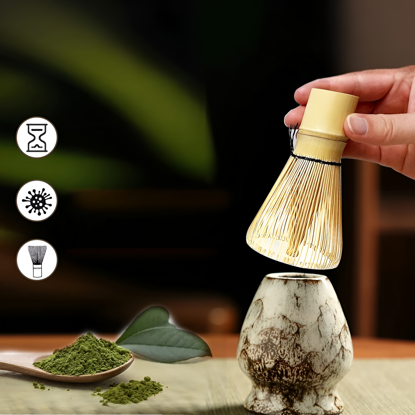 Hand holding a bamboo matcha whisk over a rustic ceramic bowl, with green matcha powder on a wooden spoon nearby.
